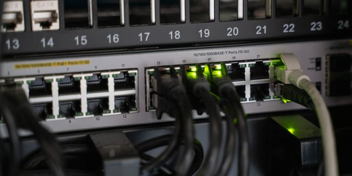 A patch panel above a network switch, a handful of ports lit green and in use, most of them empty